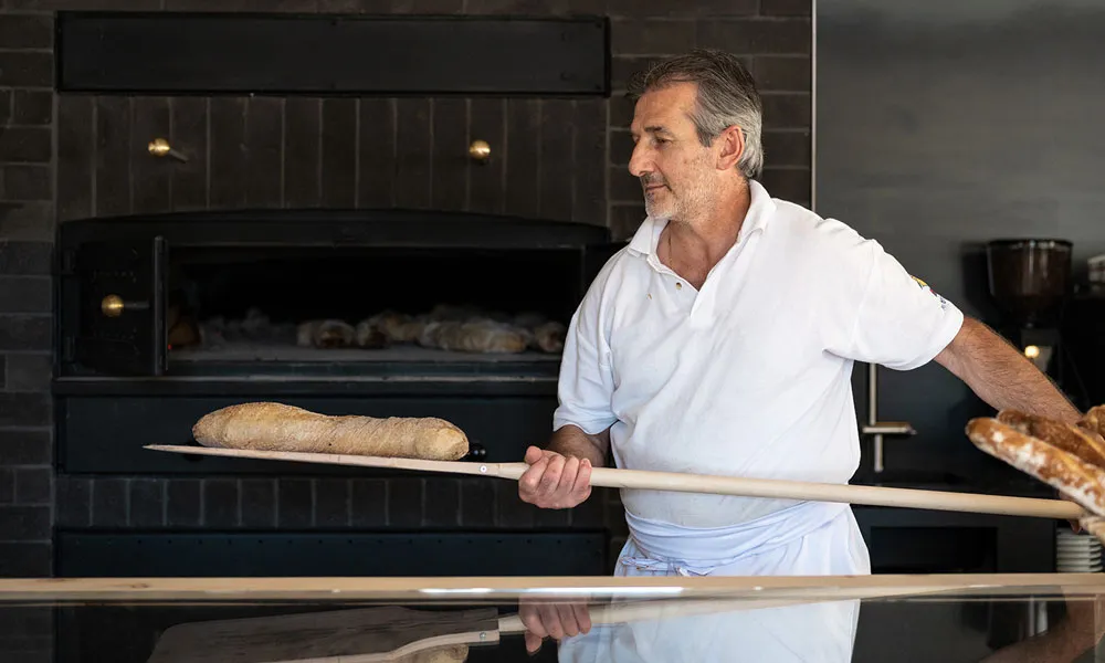 Bäcker holt Brot aus dem Holzofen